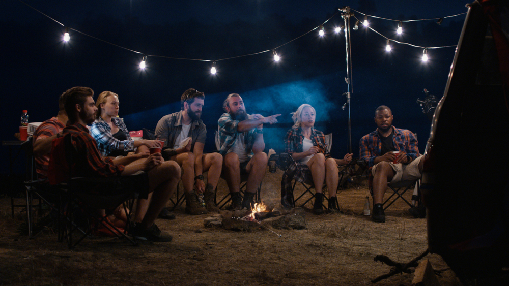 People sat round a camp fire watching a movie.